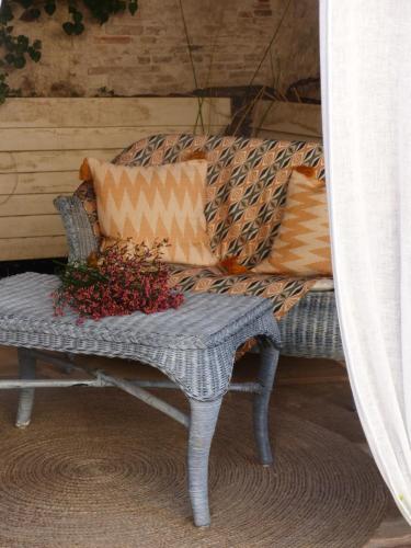 a wicker bench with pillows and flowers on it at Le voyage d'UBUNTU in Heiligenstein