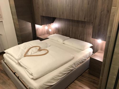 uma grande cama branca com uma almofada de coração em Genziana 2 em Ponte di Legno