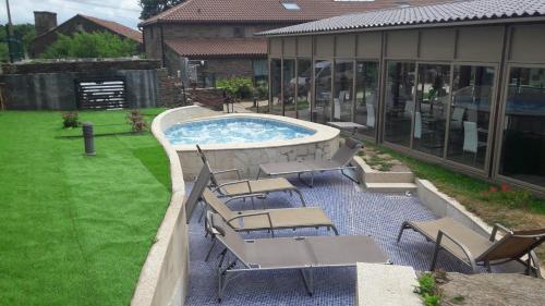 a patio with chairs and a pool and a building at Albergue Turistico Salceda in Salceda