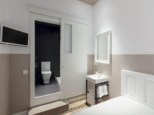 a bathroom with a toilet and a sink and a mirror at Ecozentric in Barcelona