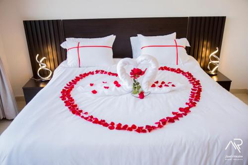 un letto bianco con un cuore fatto di rose di Aspar Resorts a Riyad