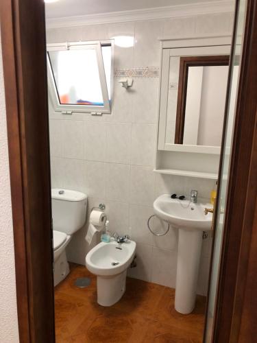 y baño con aseo, lavabo y espejo. en Apartamento playa arinaga en Arinaga