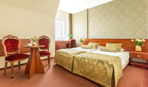 a bedroom with a bed and a table and chairs at Leśna Perła - Restauracja i Pokoje Hotelowe in Rudzinitz
