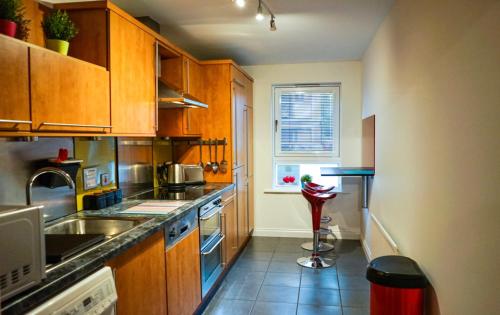 a kitchen with wooden cabinets and a sink and a stove at Hydro Apartment with free car park in Glasgow