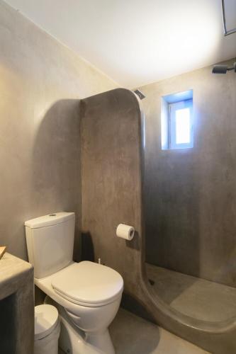 a bathroom with a toilet and a shower with a window at L’arco Milos Suite in Adamas