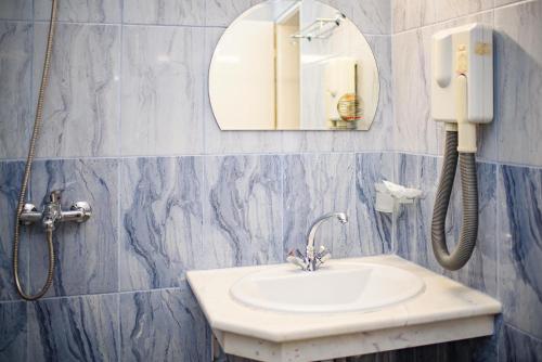 ein Badezimmer mit einem Waschbecken und einem Telefon an der Wand in der Unterkunft Family Hotel Varna in Warna