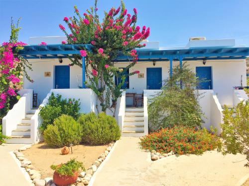 a house with white walls and blue doors and flowers at Firoa Studios in Donoussa
