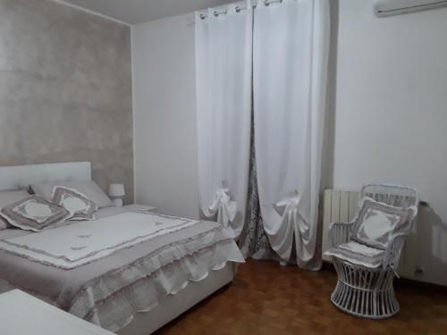 a white bedroom with a bed and a chair at B&B LA ROSA GIALLA in Maranello