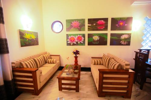 a living room with couches and tables and paintings at SRI LANKAN VILLA in Galle