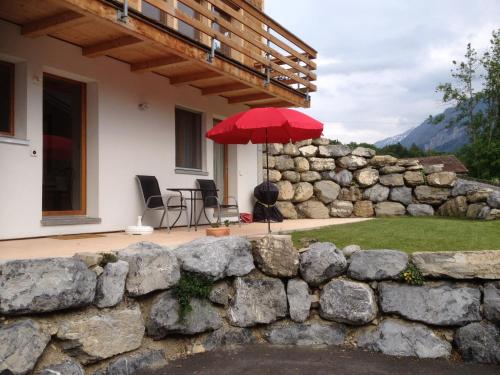 a house with a stone wall and an umbrella at Chalet Mack in Brienzwiler