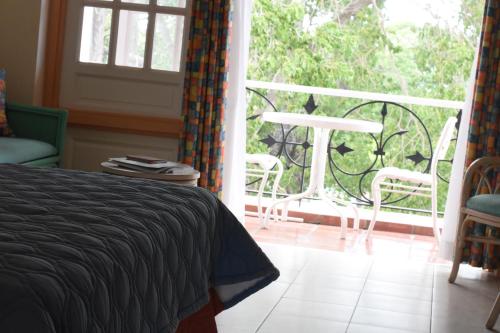 a bedroom with a bed and a balcony with a table and chairs at Hotel PomMarine in Bridgetown