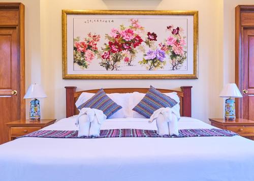 a bedroom with a white bed with a picture of flowers at Mina Garden Villa Resort in Chiang Mai