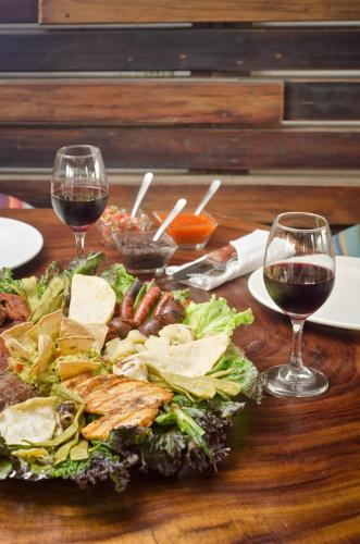 a table with two glasses of wine and a plate of food at Bungalows Zicatela in Puerto Escondido