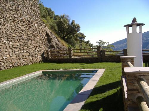 a swimming pool in a yard next to a stone building at Estrella de las Nieves in Pampaneira