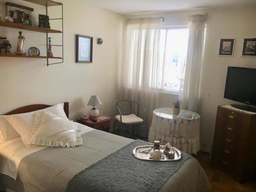 1 dormitorio con 1 cama, TV y mesa en Hostal Don Mariano en Concepción