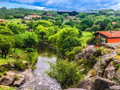 a river in a park with trees and houses at Los Ancares Resort in Mina Clavero