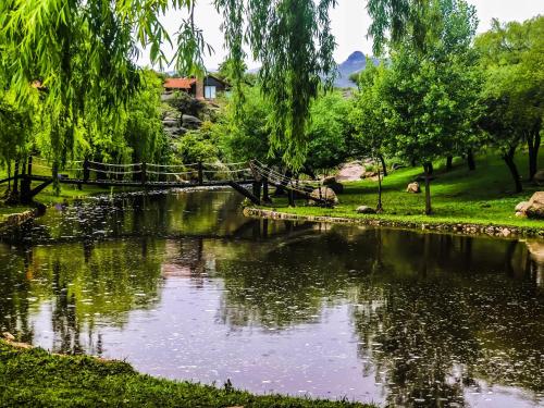 a bridge over a river in a park at Los Ancares Resort in Mina Clavero