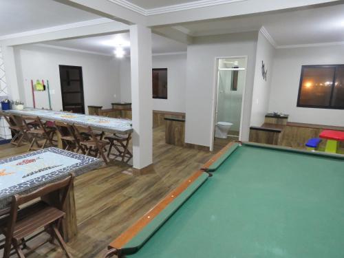 a pool table in a room with tables and chairs at Residencial Sol e Lua in Palhoça