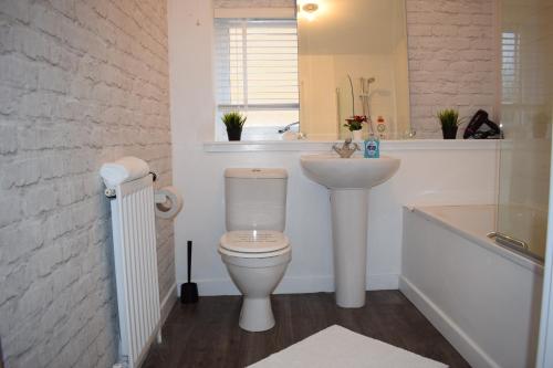 a bathroom with a white toilet and a sink at Silverburn new house with free parking and nice garden in Glasgow