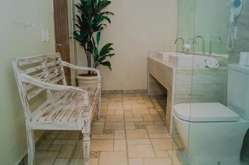 a bathroom with a toilet and a sink and a chair at Pousada La Dolce Vita in Búzios