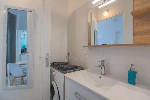 W białej łazience znajduje się umywalka i lustro. w obiekcie studio marine 100m plage w mieście Royan