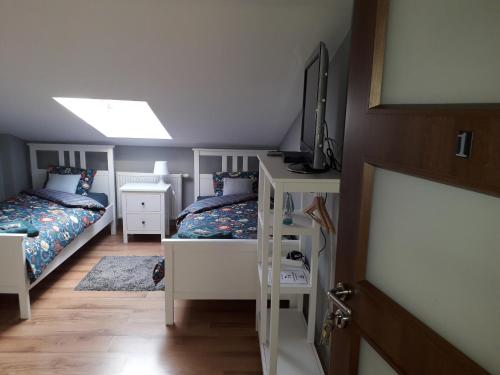 a bedroom with two beds and a television on a shelf at NaNoc - noclegi obok lubelskich szpitali i centrum Lublina in Lublin
