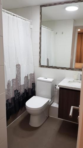 Un baño con inodoro, lavabo y espejo. en Departamento Central Uno Norte Viña del Mar, en Viña del Mar