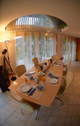a dining room table with chairs and a long table with plates and chopsticks at Bed and Breakfast La Petite Thielle in Cressier