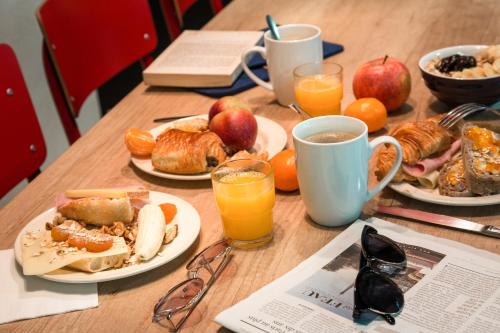 a wooden table with plates of breakfast food and orange juice at ibis Styles Chartres Métropole in Chartres