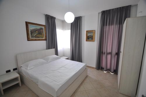 a bedroom with a white bed and a window at Aparthotel Shkodra in Durrës