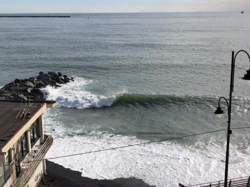 a wave in the ocean next to a building at La Casetta di Dory sul Mare in Genova