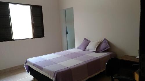 a bedroom with a purple and white bed with a window at Quarto para uma pessoa com banheiro exclusivo in Alfenas