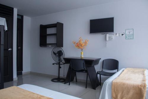 a bedroom with a desk and a tv on the wall at Hotel Escorial Ibague in Ibagué