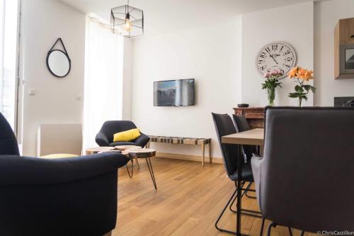a living room with a table and chairs and a clock at Résidence le XV in Bagnères-de-Bigorre