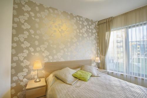 Schlafzimmer mit einem Bett mit einer blumengeschmückten Wand in der Unterkunft Apartamentai Liuks in Druskininkai