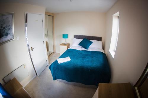 a bedroom with a large bed with a blue blanket at Baystays Scenic View in Swansea