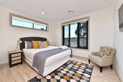 a bedroom with a bed and a chair and a window at Horizon 7 in Pokolbin