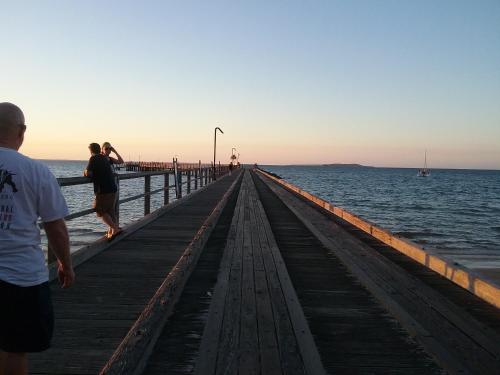 two people walking on a pier over the water at Urangan Motor Inn in Hervey Bay