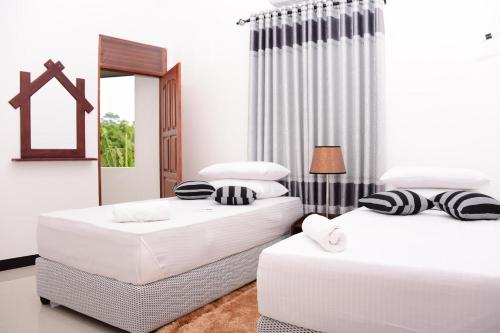 2 camas en una habitación con paredes blancas en Richmond Hillside, en Galle