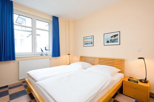 - une chambre avec un grand lit blanc et des rideaux bleus dans l'établissement Villa Hildegard Appartement 7- Strand 200 Meter-Zentrum von Binz, à Binz