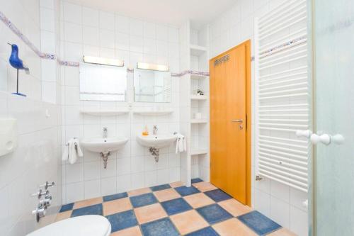 La salle de bains est pourvue de 2 lavabos et d'une porte orange. dans l'établissement Villa Hildegard Appartement 7- Strand 200 Meter-Zentrum von Binz, à Binz