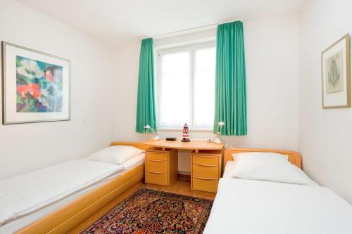 2 Betten in einem Zimmer mit grünen Vorhängen und einem Tisch in der Unterkunft Villa Hildegard Appartement Nr. 1 in Binz