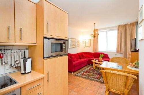eine Küche und ein Wohnzimmer mit einem roten Sofa in der Unterkunft Villa Hildegard Appartement Nr. 1 in Binz