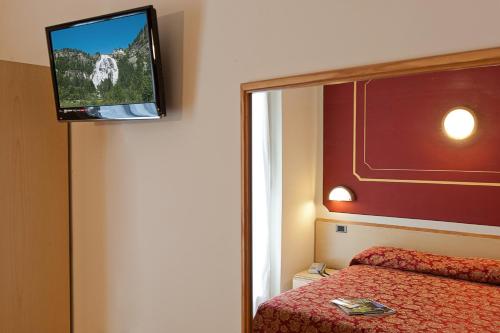 a room with a bed and a television on the wall at Hotel Boston in Stresa