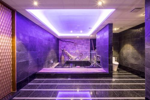 a purple bathroom with a tub with a giraffe on the wall at Merry Day Motel Zhonghe Branch in Zhonghe