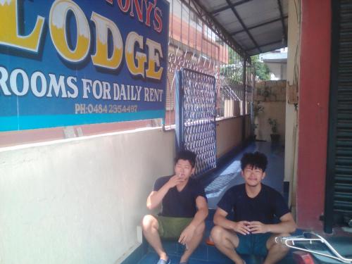 two men sitting on the steps of a store at St. Antonys Lodge in Cochin