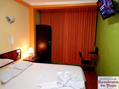 a bedroom with a white bed with a bow on it at Sombrero de Paja in Chiclayo