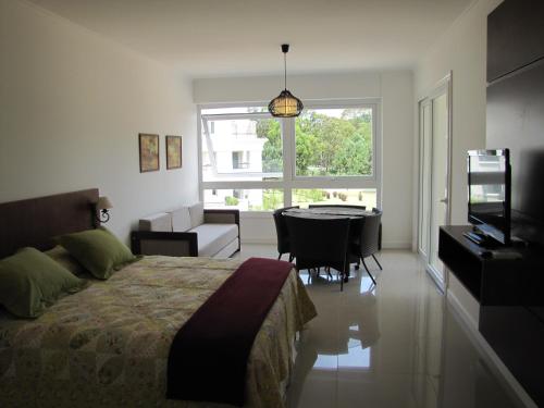 Schlafzimmer mit einem Bett, einem Tisch und einem TV in der Unterkunft Green Park Apartamentos in Punta del Este