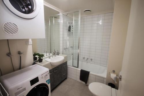 uma casa de banho com um lavatório e uma máquina de lavar roupa em Onsite Parking, Self Check-in em Melbourne