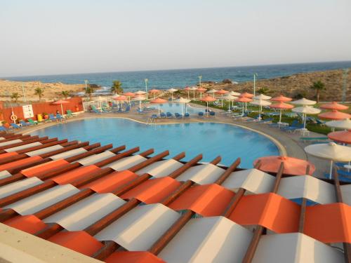 a view of a swimming pool with umbrellas and the ocean at Aktea Beach Village in Ayia Napa